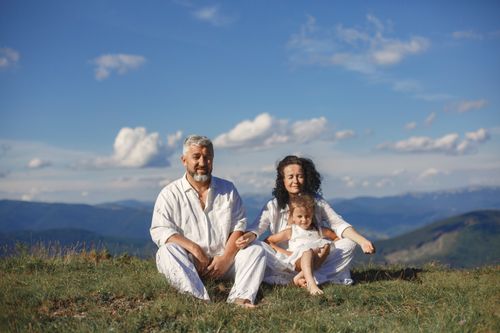 Free A happy family enjoys a sunny day outdoors, sitting together on a grass field. Stock Photo