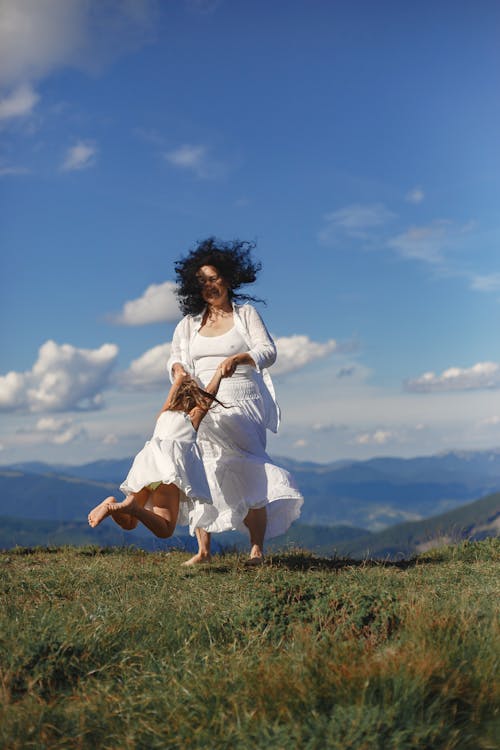 Woman in White Dress Playing with Her Granddaughter on Green Grass