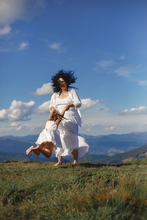 Free Grandmother and granddaughter joyfully spinning on a summer day in open nature. Stock Photo