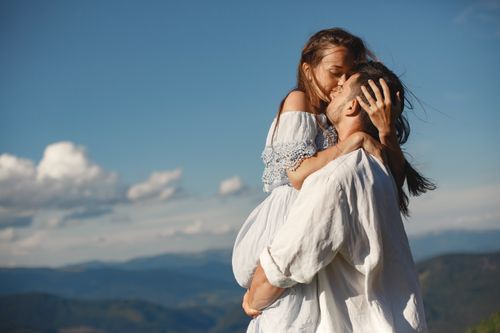 Free A couple sharing a romantic embrace on a scenic mountain top with a clear blue sky. Stock Photo