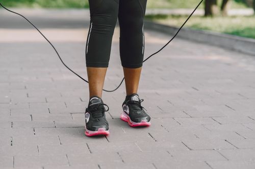 Free Close-up of feet in sneakers jumping rope on outdoor pavement. Stock Photo