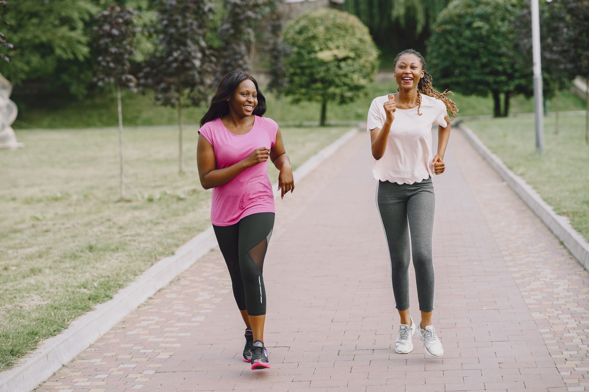 A small group of women running together along a park path in early morning light