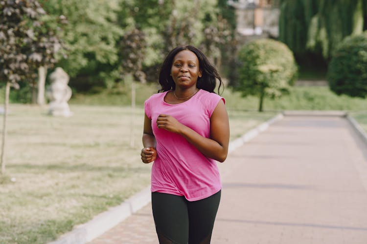 Woman In Pink Shirt And Black Leggings Jogging