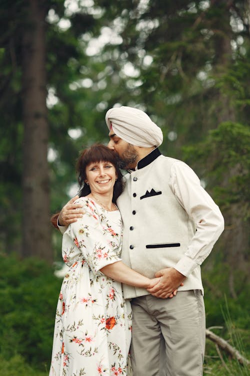 Free Man Kissing Woman in White and Red Floral Dress Stock Photo