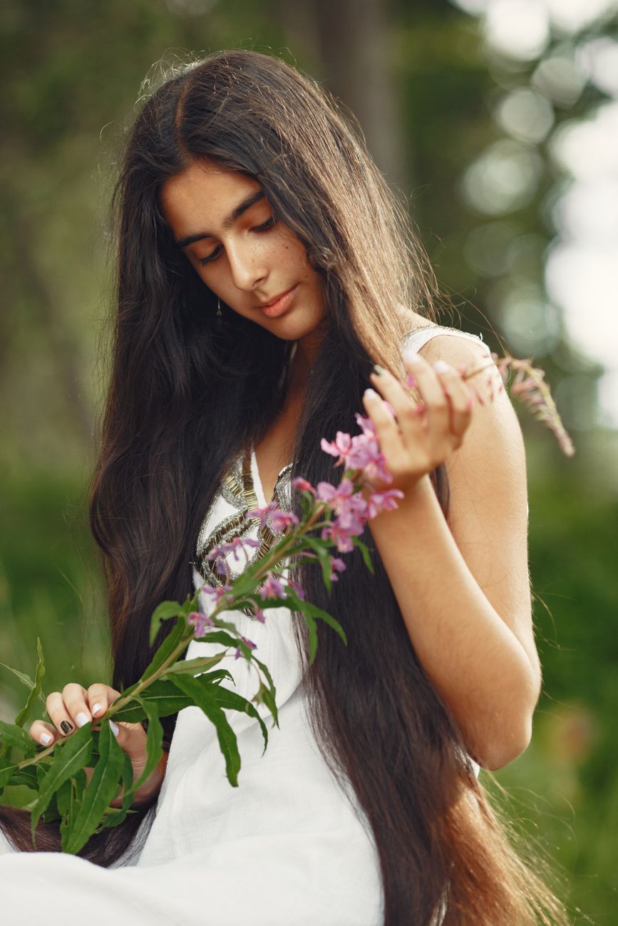 A woman with long hair enjoys a peaceful moment with nature, holding vibrant wildflowers.