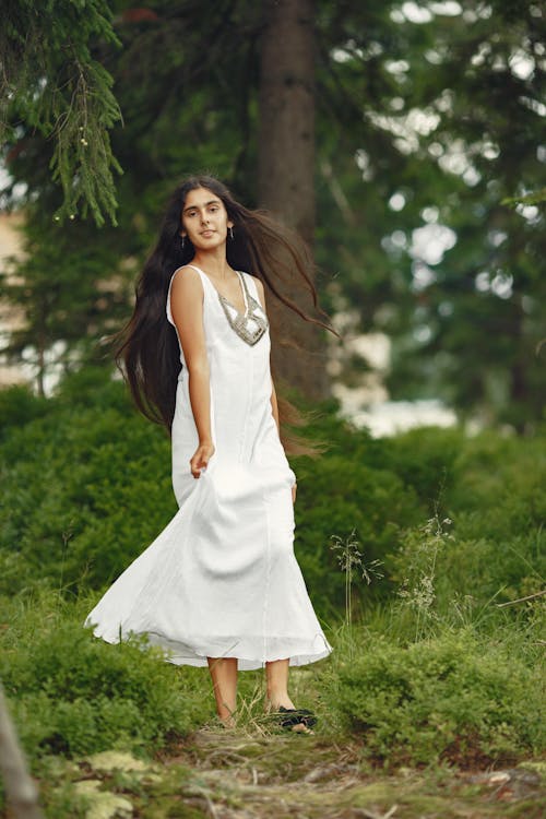Woman in White Sleeveless Dress Standing on Green Grass