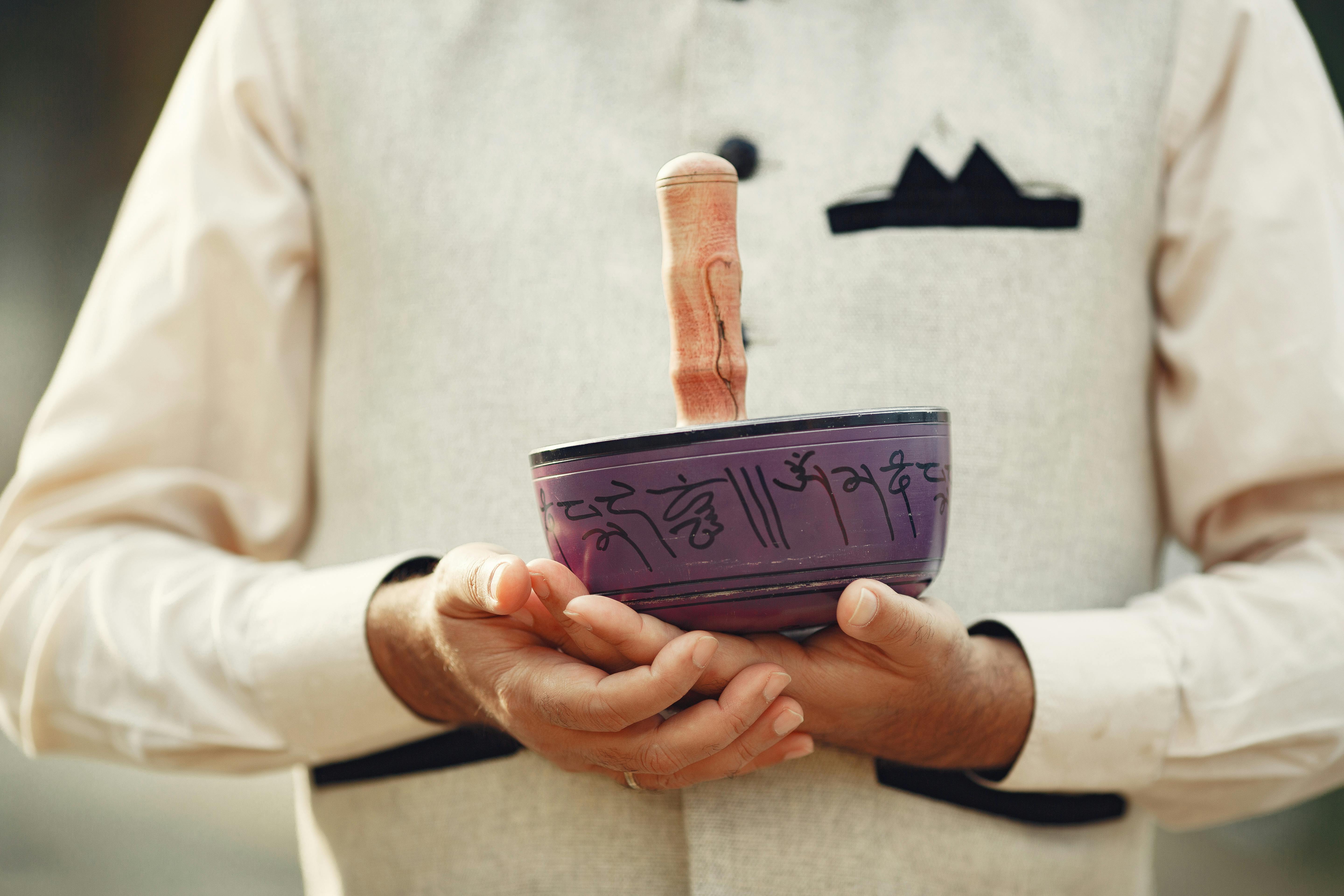 Hands holding a Tibetan singing bowl, showcasing a traditional meditation and relaxation instrument.