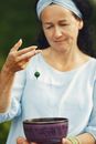 A Woman Holding a Bead Over the Metal Bowl