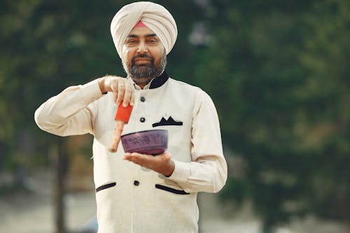 A Man Wearing Turban and Long Sleeves Holding a Metal Bowl
