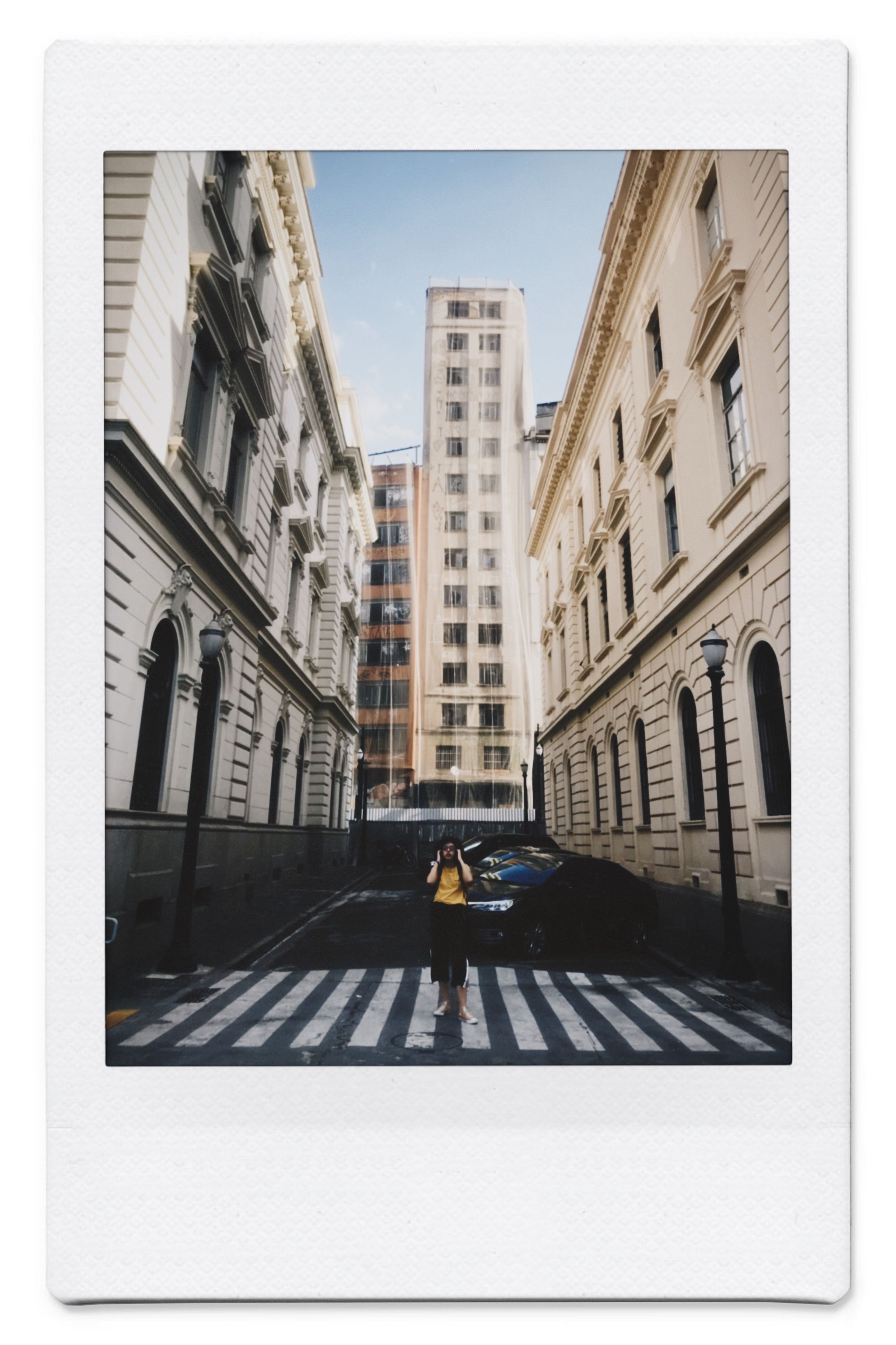 Polaroid of a city street with vintage buildings and a pedestrian crossing.