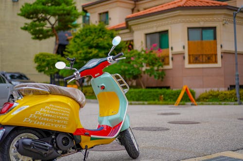 Red and Yellow Motor Scooter Parked on Gray Asphalt Road