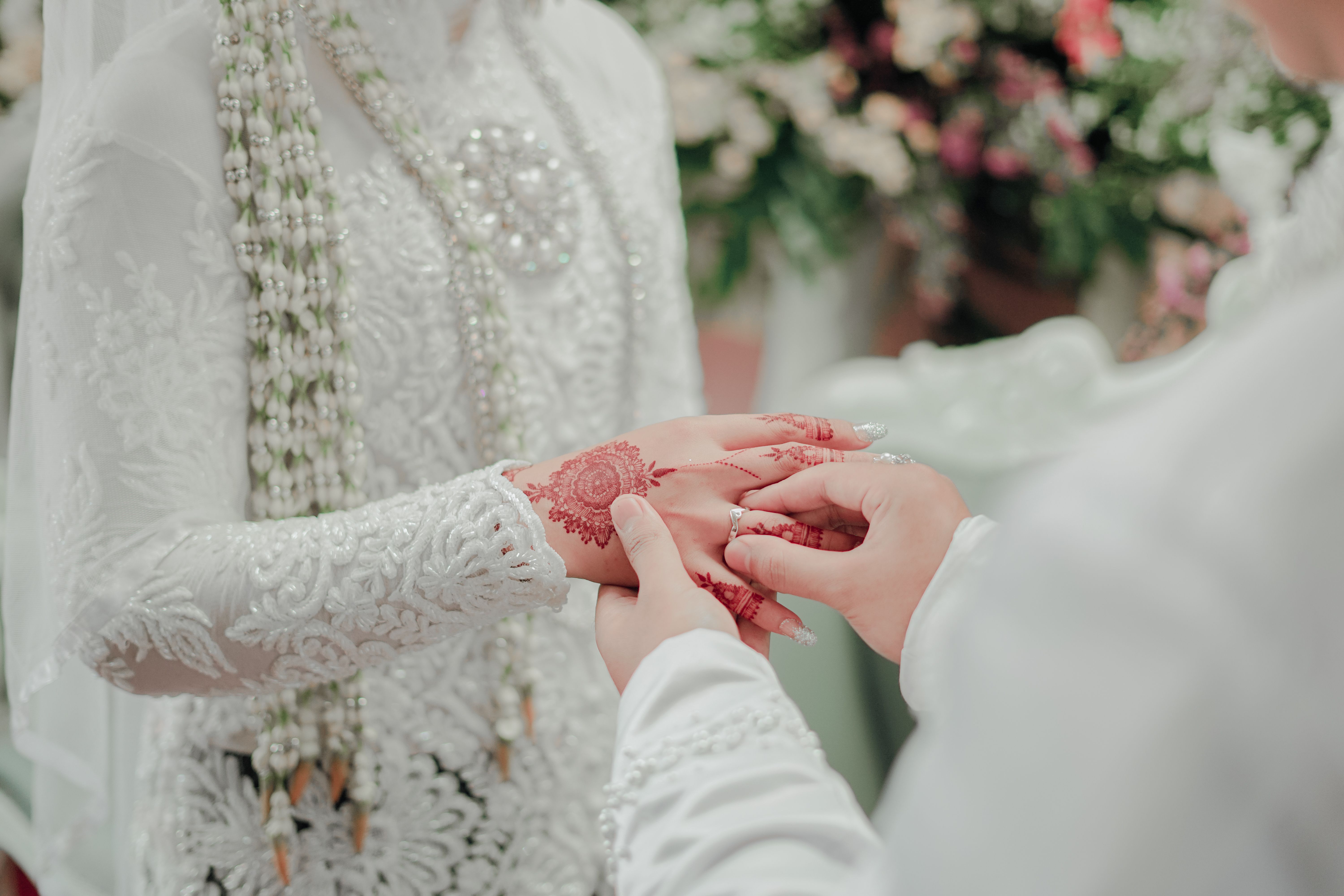 Close-up of mehndi-adorned bride's hands during a traditional wedding ceremony, symbolizing love and unity.