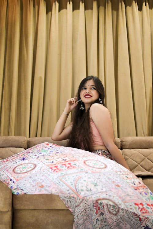 Cheerful young Indian woman sitting on sofa
