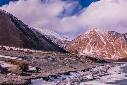 Breathtaking view of snow-capped mountains in Leh, capturing the serene winter beauty with dramatic skies.