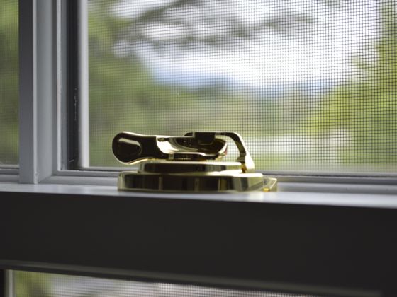Close-up of a brass latch on a closed window
