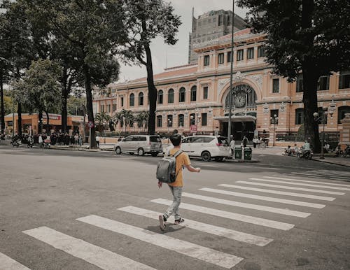 Man in Yellow T-shirt and Denim Jeans Walking on Pedestrian Lane