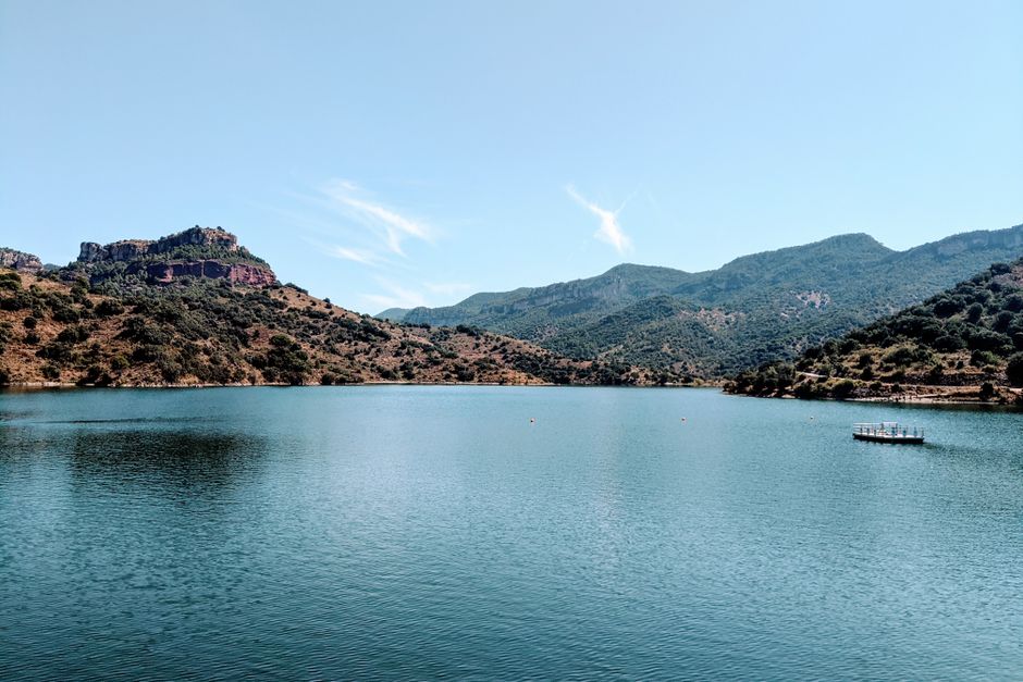 Serene landscape of a tranquil lake surrounded by lush hills in Cornudella de Montsant, Spain.