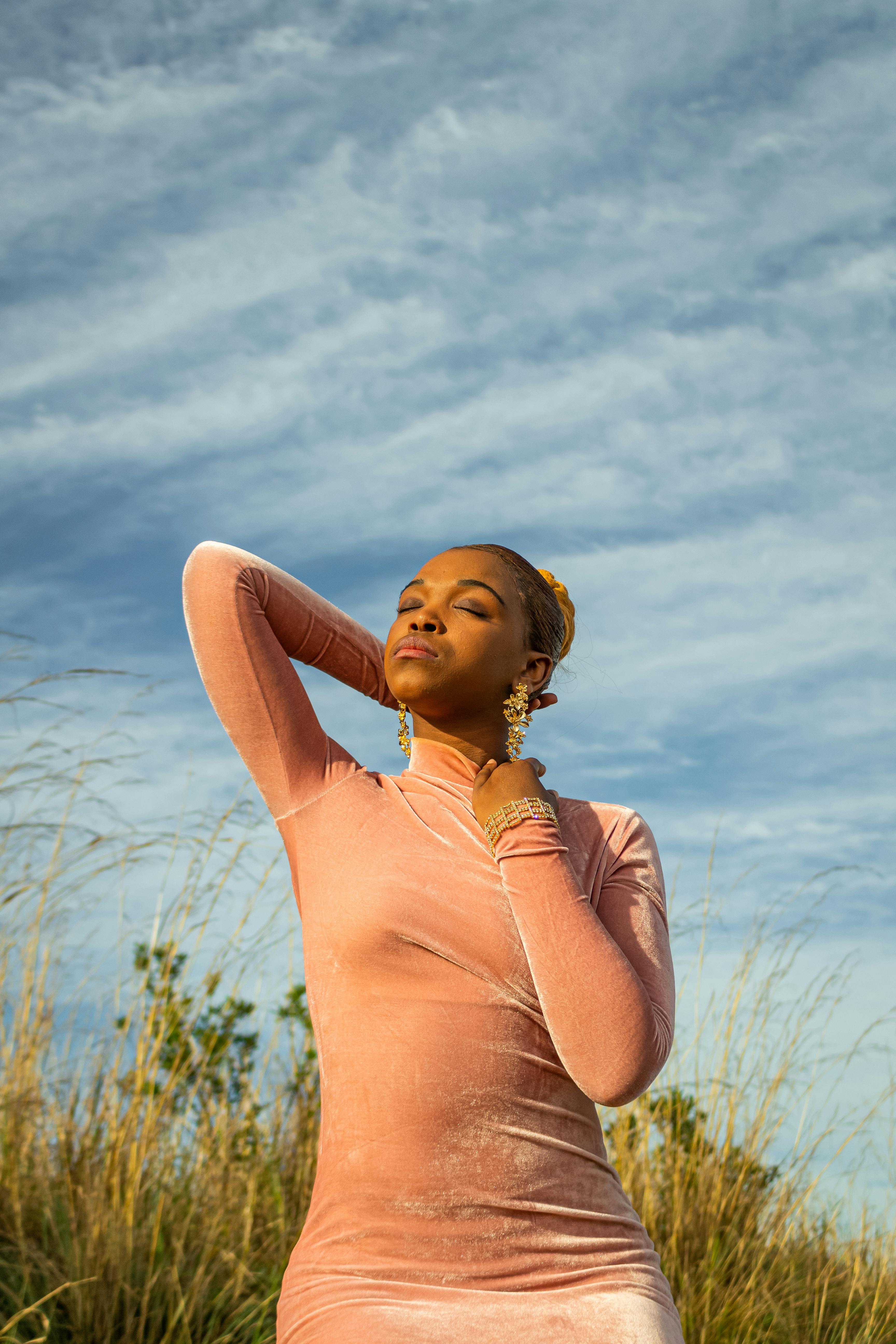 Woman in Pink Dress Standing on Green Grass Field