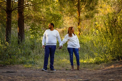 Free Man in White Long Sleeve Shirt and Blue Denim Jeans Standing Beside Woman in White Long Sleeve Sweater Stock Photo