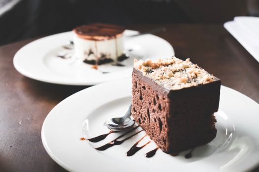 Indulgent chocolate and tiramisu desserts on plates with chocolate drizzle.