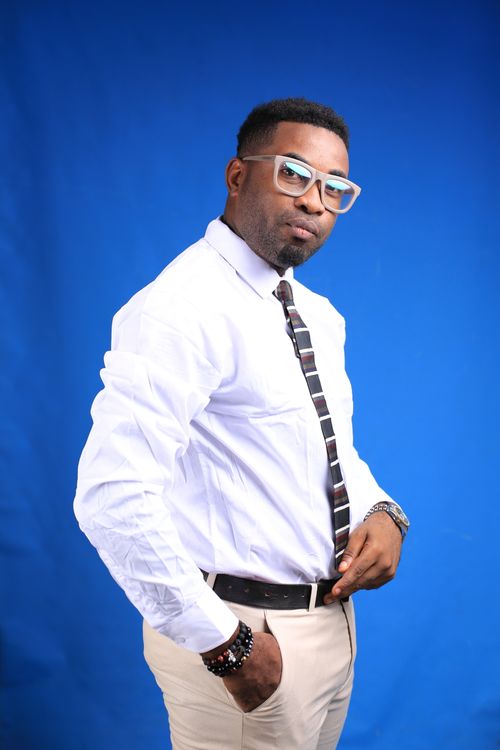Free A confident man wearing glasses and a formal outfit poses against a blue background, exuding a serious demeanor. Stock Photo