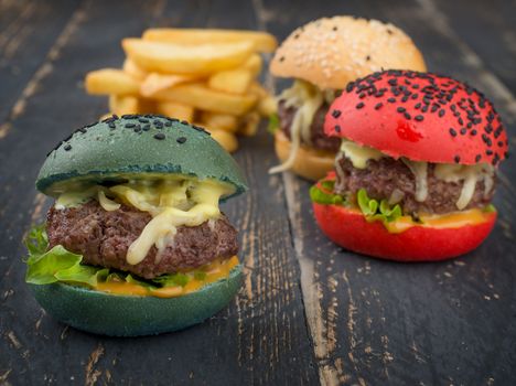 Vibrant gourmet burgers with colorful buns and cheese, served with crispy fries on a rustic surface.