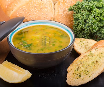 Delicious bowl of vegetable soup served with garlic bread and fresh greens.