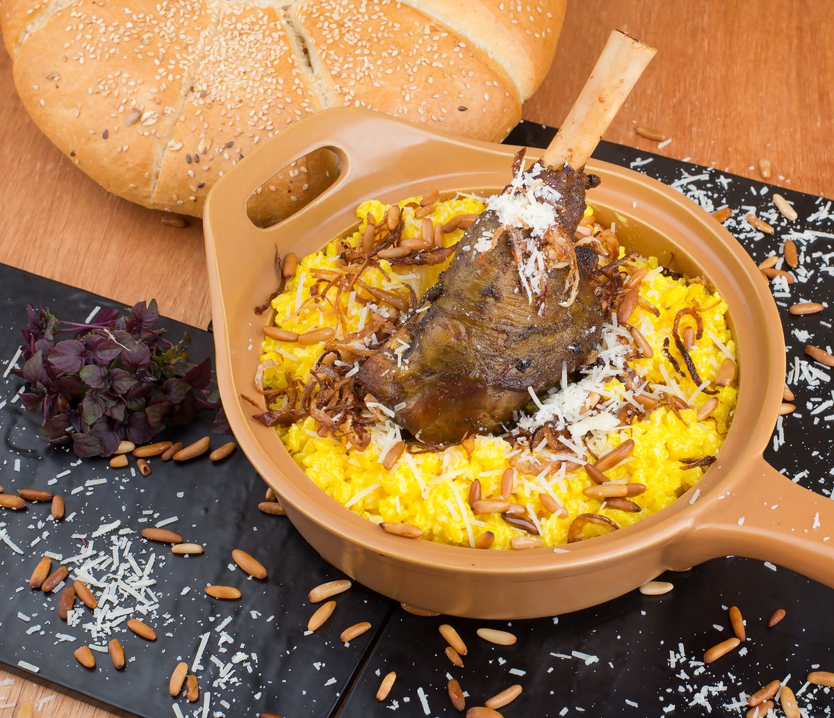 Roasted lamb shank on yellow saffron rice with fried onions, almonds and grated cheese