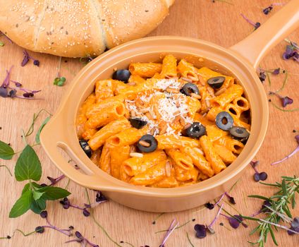Delicious creamy rigatoni pasta with olives served next to fresh sesame bread.