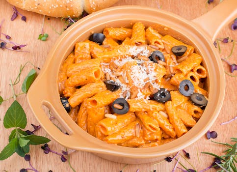 Delicious creamy rigatoni pasta served with black olives, pine nuts, and grated cheese.