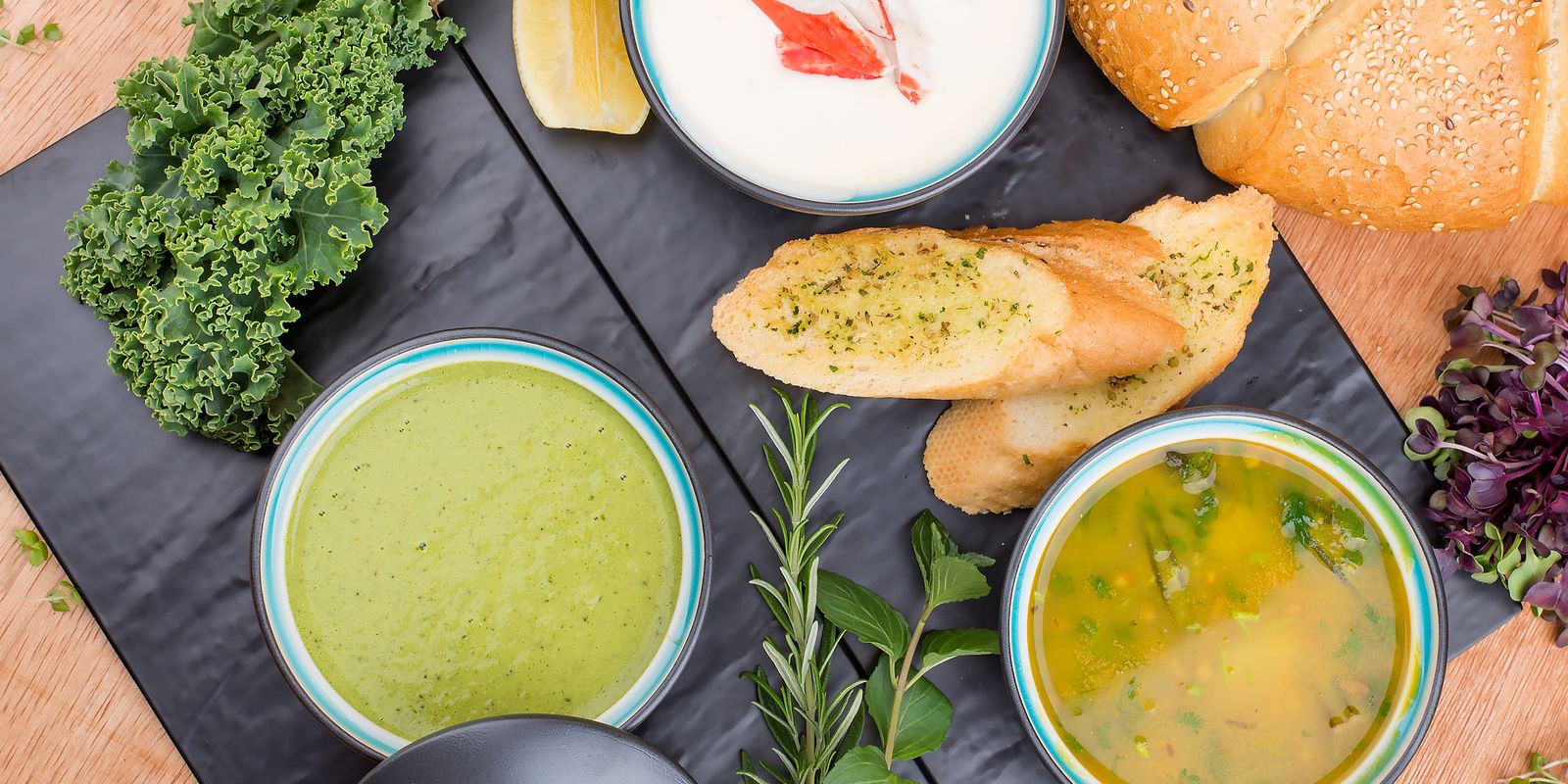 Gourmet soups with fresh bread and herbs on a wooden table