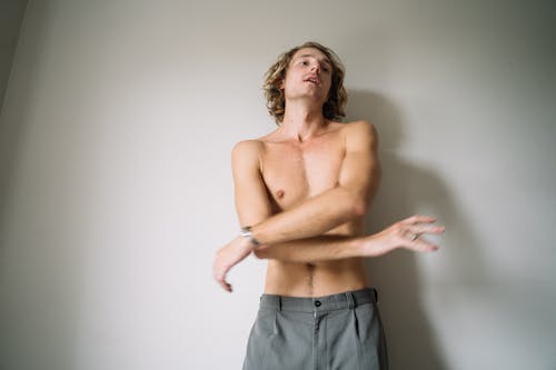 Free Topless Man in Gray Bottom Standing Near White Wall Stock Photo