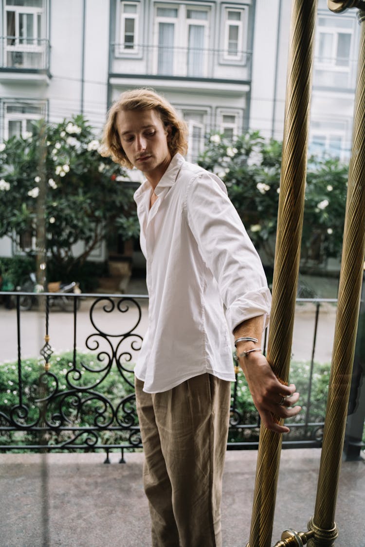 Man In White Dress Shirt And Brown Pants Holding The Door