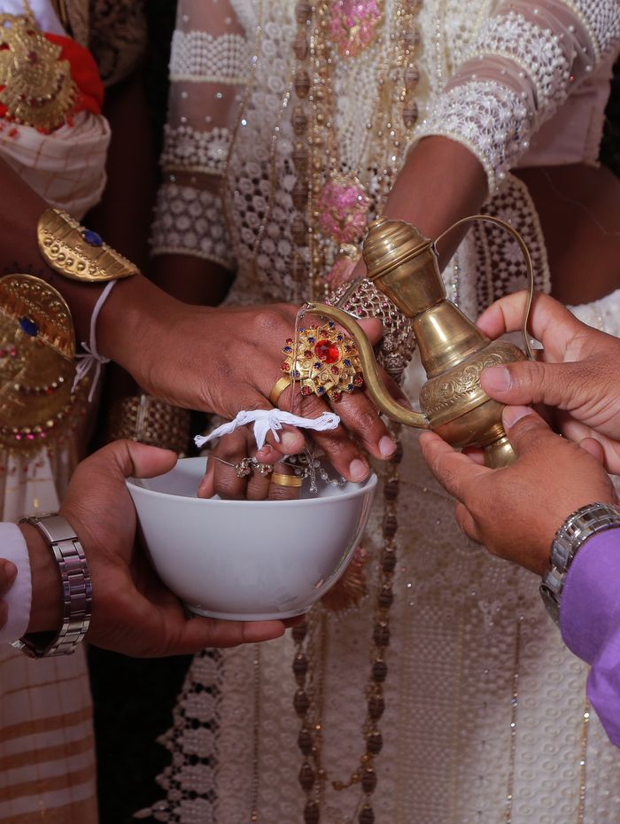 Poruwa ritual — water poured over the couple’s linked fingers from a brass kendiya