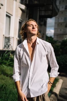 一名男子穿着白衬衫，在户外享受阳光明媚的一天，这是一幅休闲时尚肖像