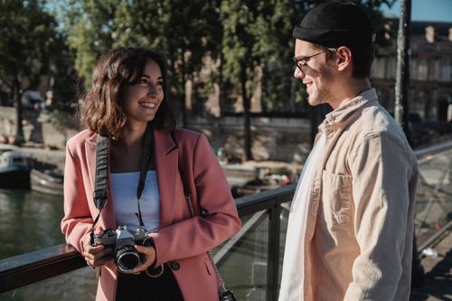 Free A happy couple smiling at each other with a camera in hand on a sunny day outdoors. Stock Photo