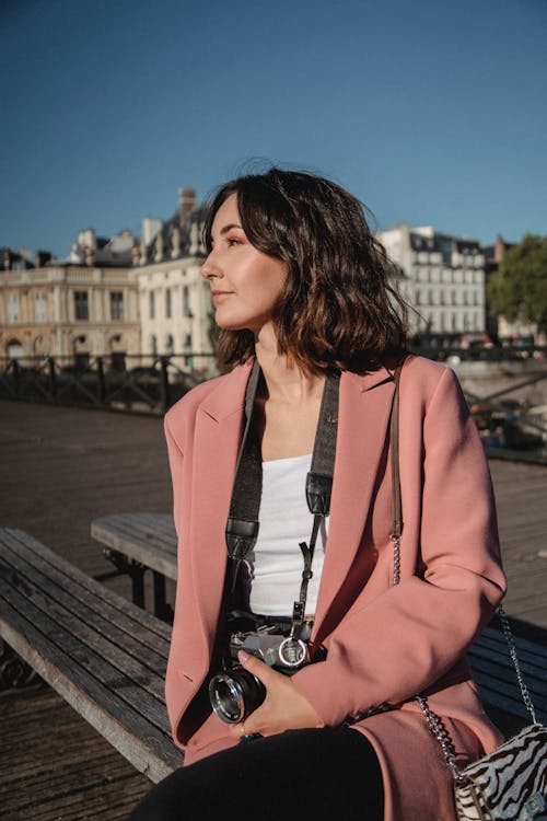 Woman in Pink Blazer Sitting on Brown Wooden Bench