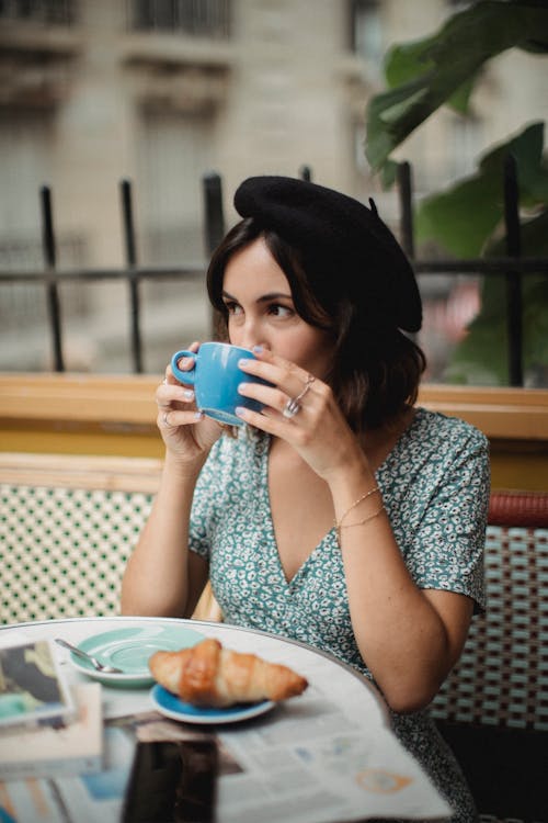 Woman in White and Blue Floral Dress Drinking from Blue Ceramic Mug