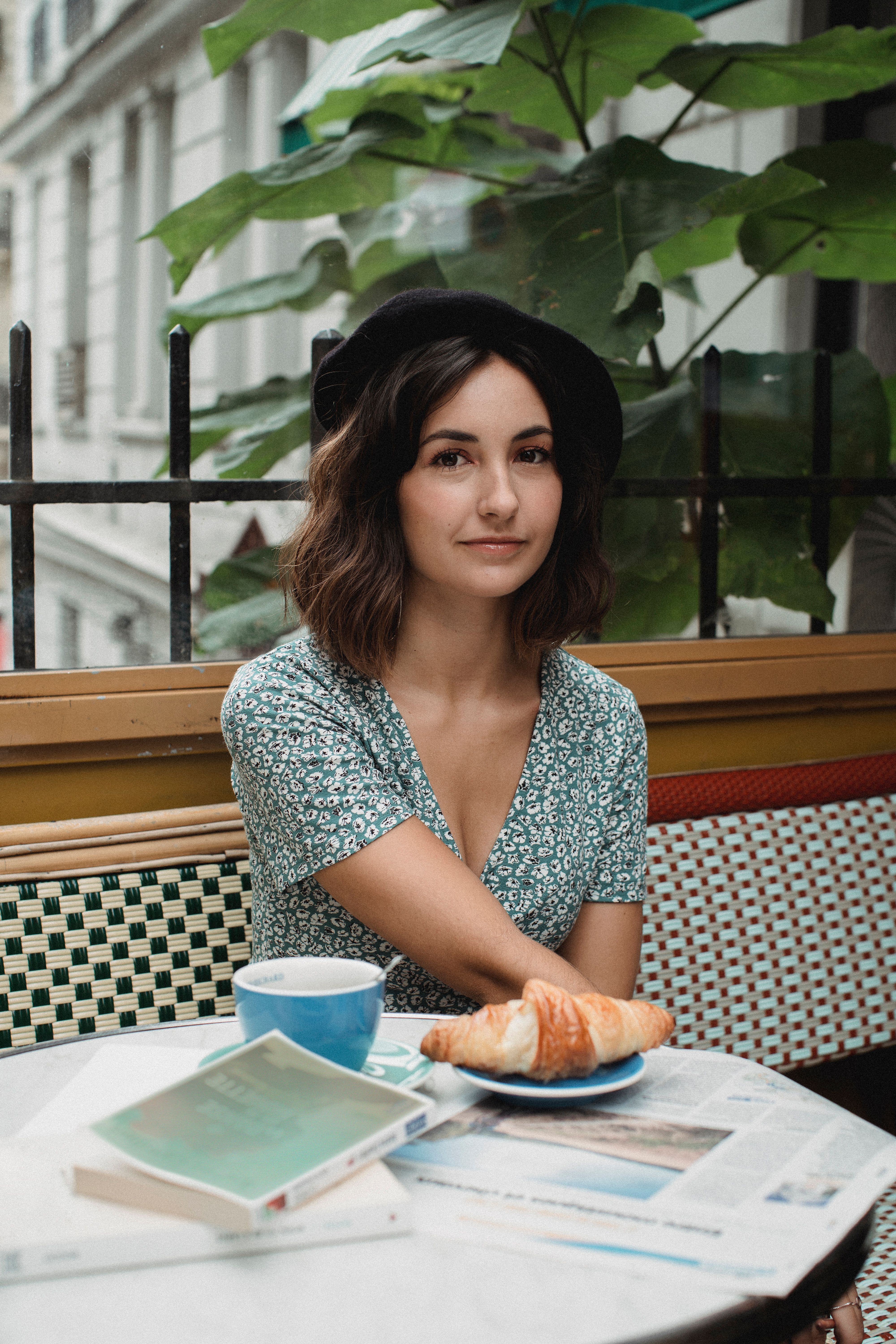Young woman in a cafe enjoys morning with coffee and croissant.