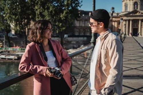Free Young couple smiling on a bridge, enjoying a sunny day with a camera in hand. Stock Photo