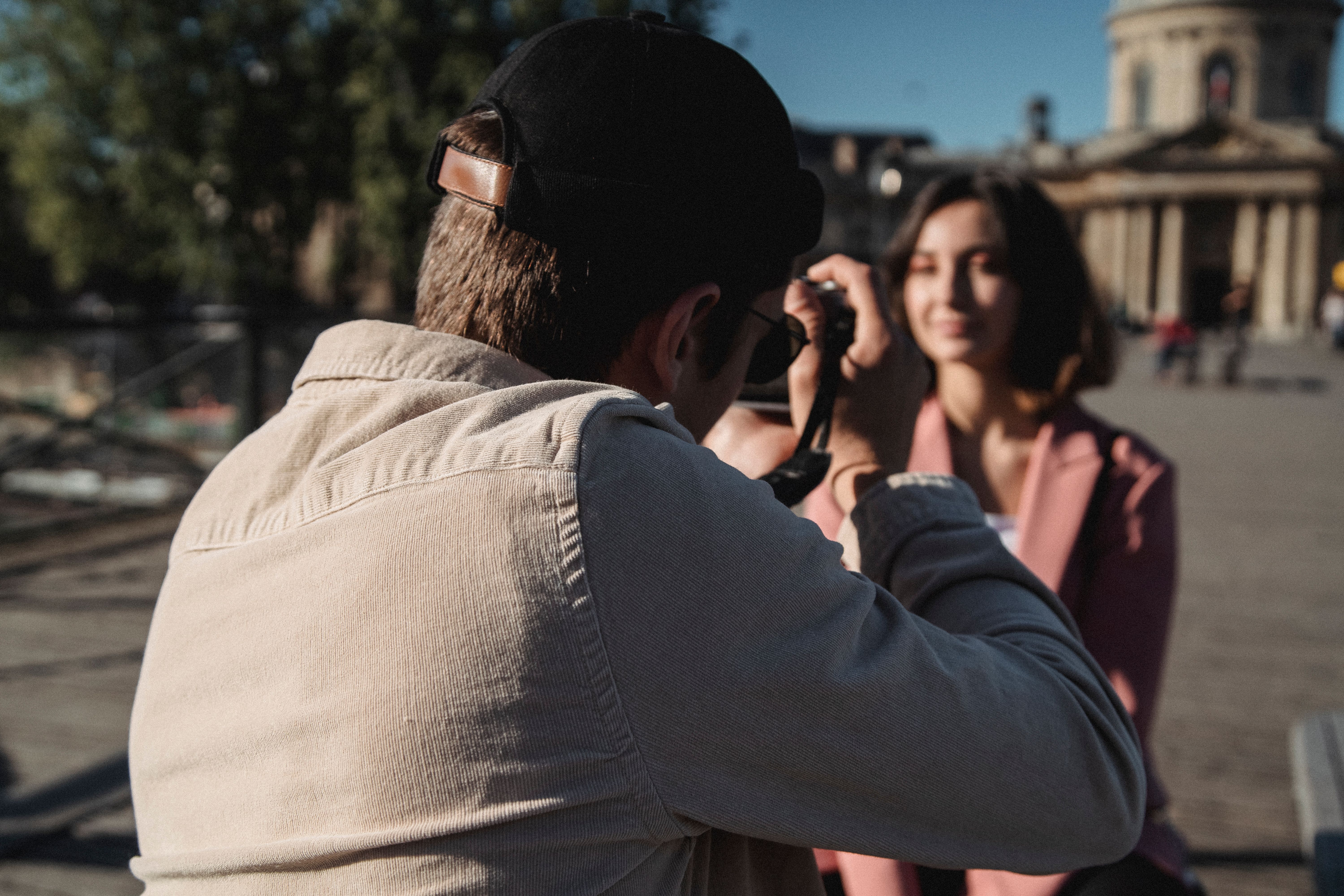 A man taking a photo of a woman outdoors on a sunny day.