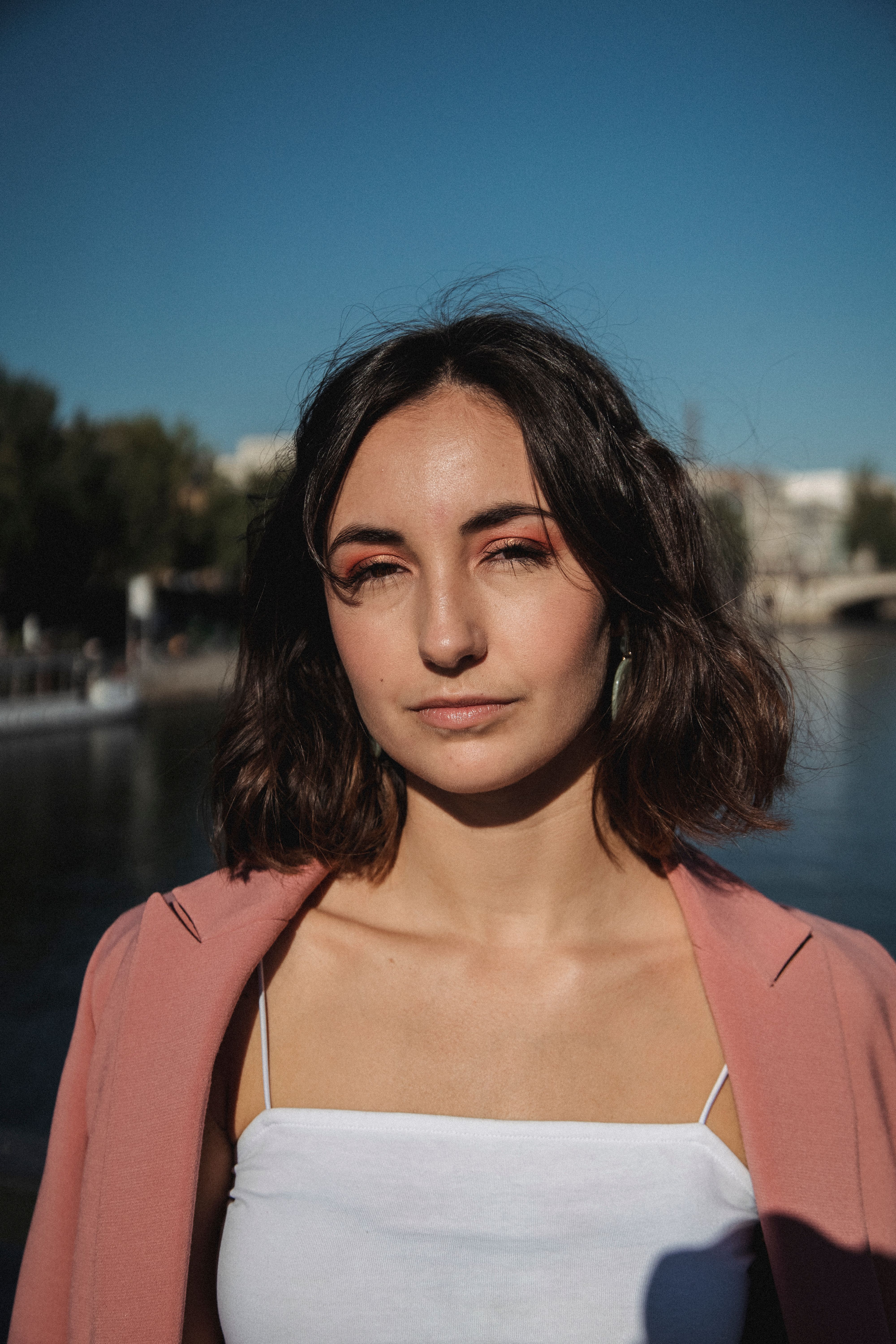 Chic portrait of a brunette woman with stylish fashion by a riverside.