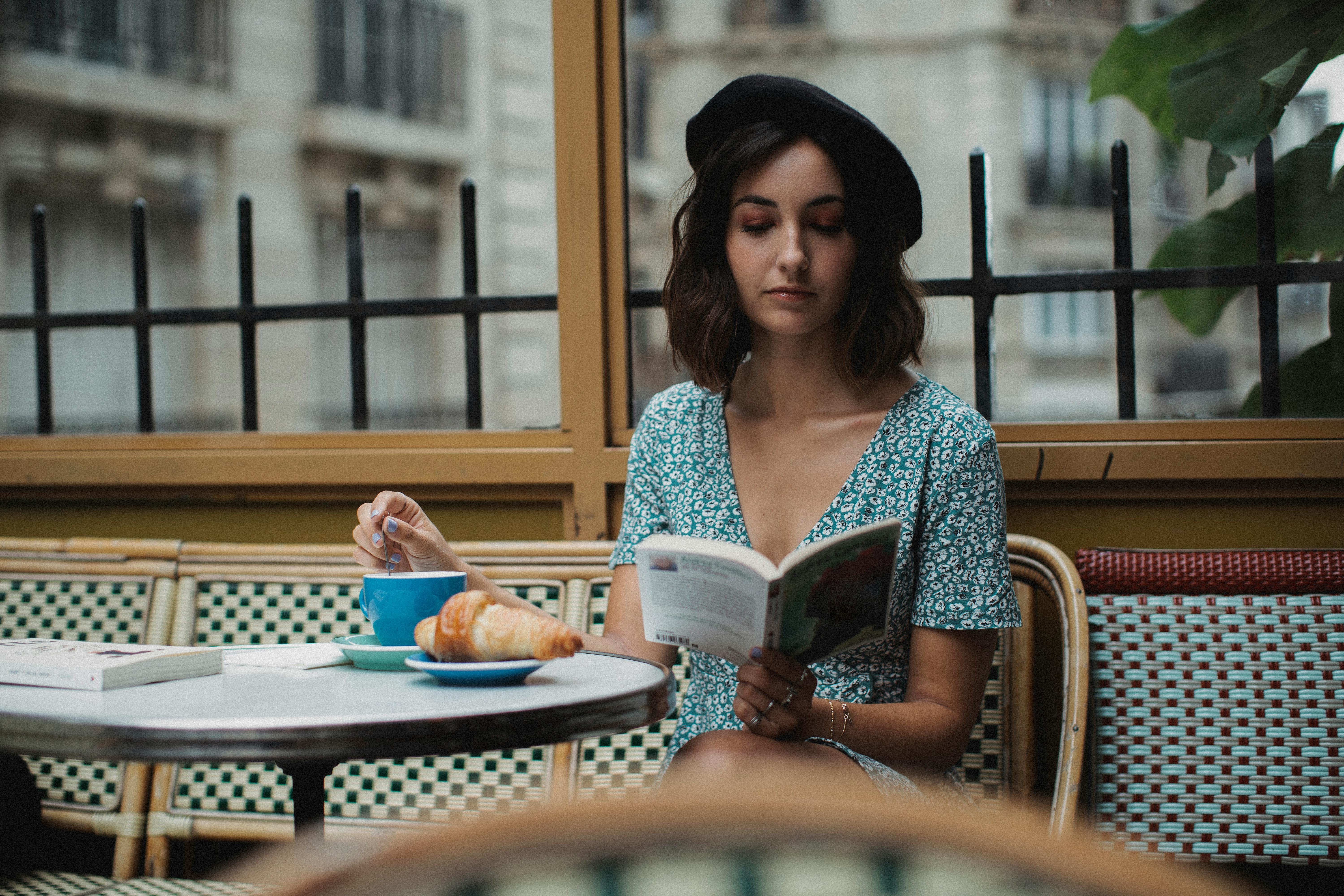 A woman enjoys a book with coffee at a Parisian cafe, exuding a calm and classic ambiance.