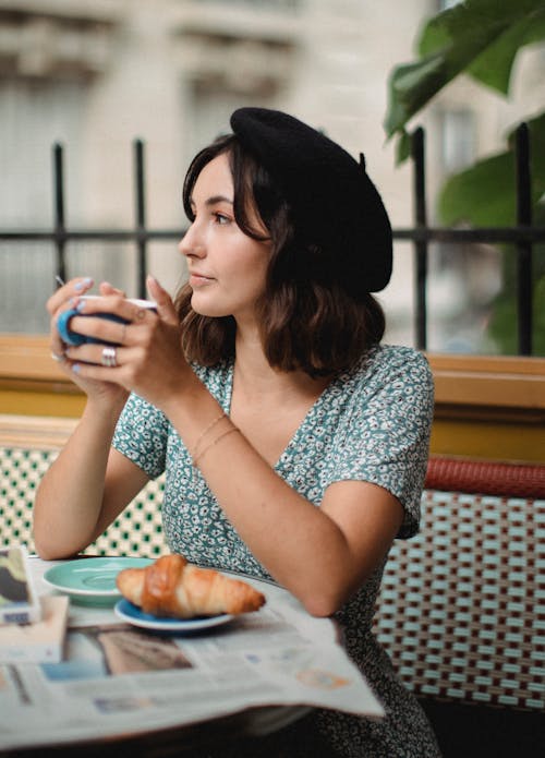 Woman in Blue and White Floral Shirt Holding a Cup