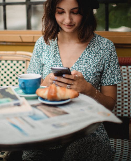 Free Woman in Blue and White Floral Dress Holding a Smartphone Stock Photo