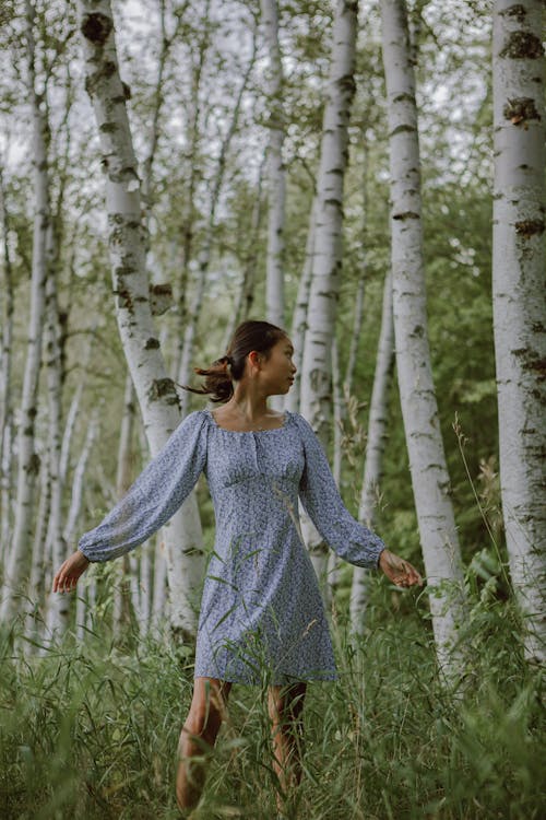 蓝色长袖连衣裙站在森林上的女人