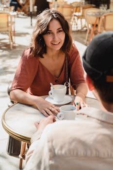 Two adults enjoying coffee at an outdoor café on a sunny day.