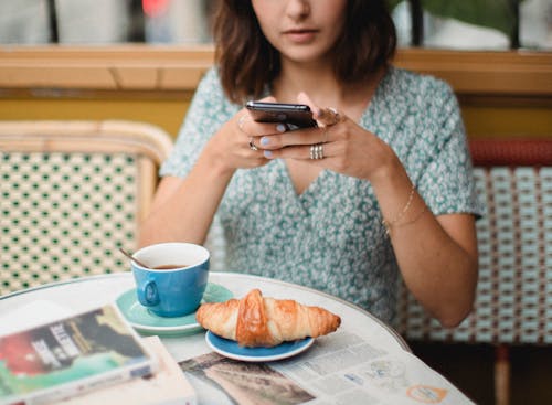 Free Woman in Blue and White Floral Dress Holding a Smartphone Stock Photo