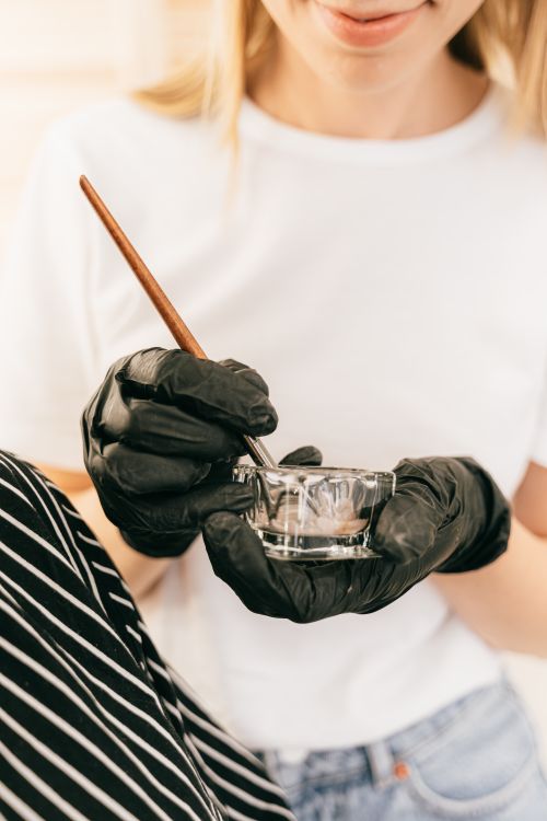 Free Close-up of a woman in gloves mixing with a brush in a glass bowl. Ideal for beauty and skincare themes. Stock Photo