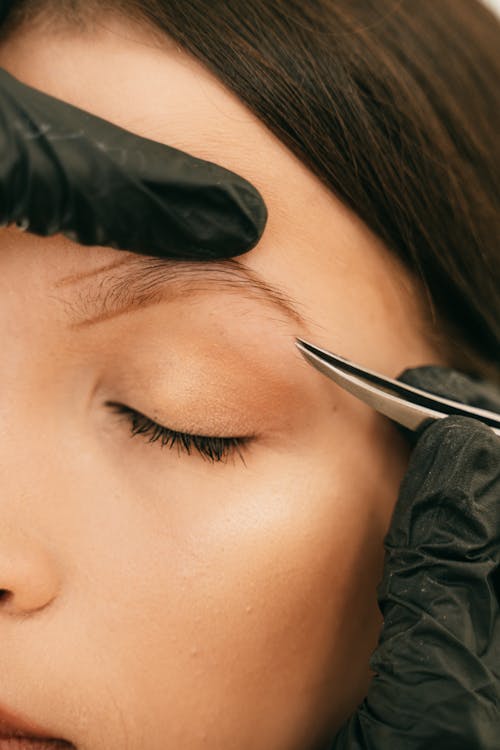 Person Plucking Woman's Eyebrow